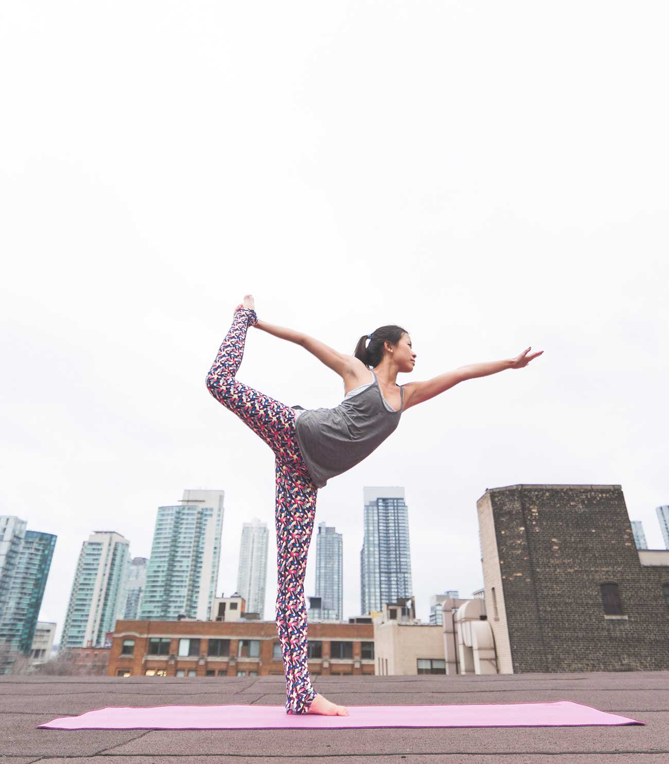 Woman on rooftop, with one leg raised in a yoga pose.